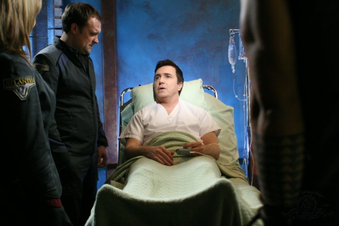 Carson (Paul McGillion) is visited by his friends in the Atlantis infirmary.
