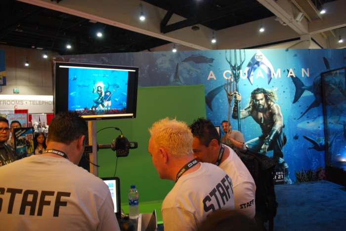 Fans get their picture taken with the Aquaman movie poster at the Warner Bros. booth

