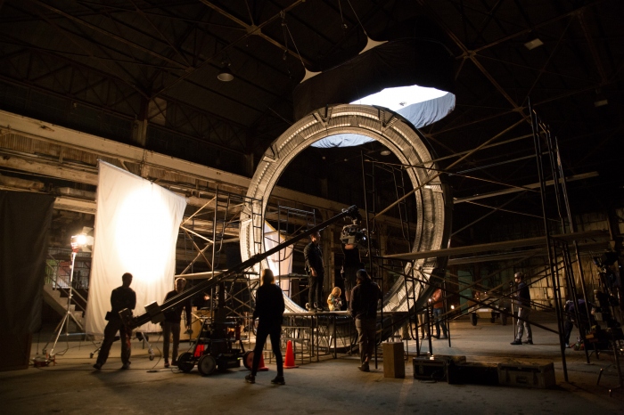 The crew surrounds the stargate as they prepare for a shot in the Langford warehouse.

